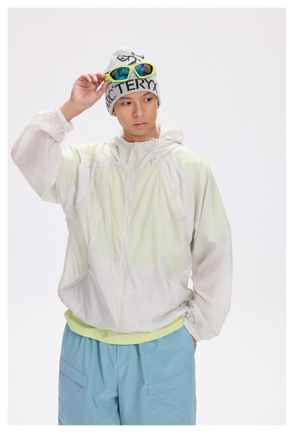 Front view of a model wearing a pale mint and white zip-front hooded jacket with elastic cuffs.
