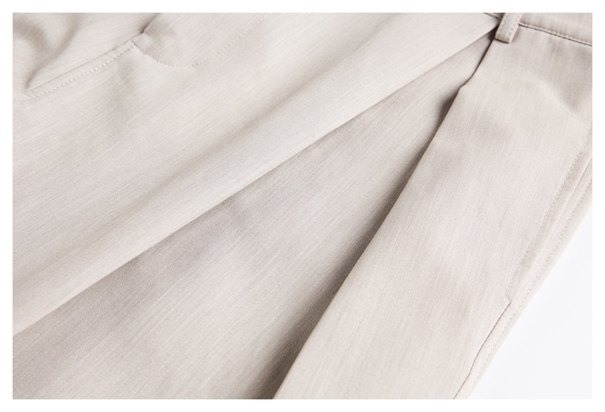 Close-up of beige trouser fabric and stitched seams, with a belt loop visible near the waistband.