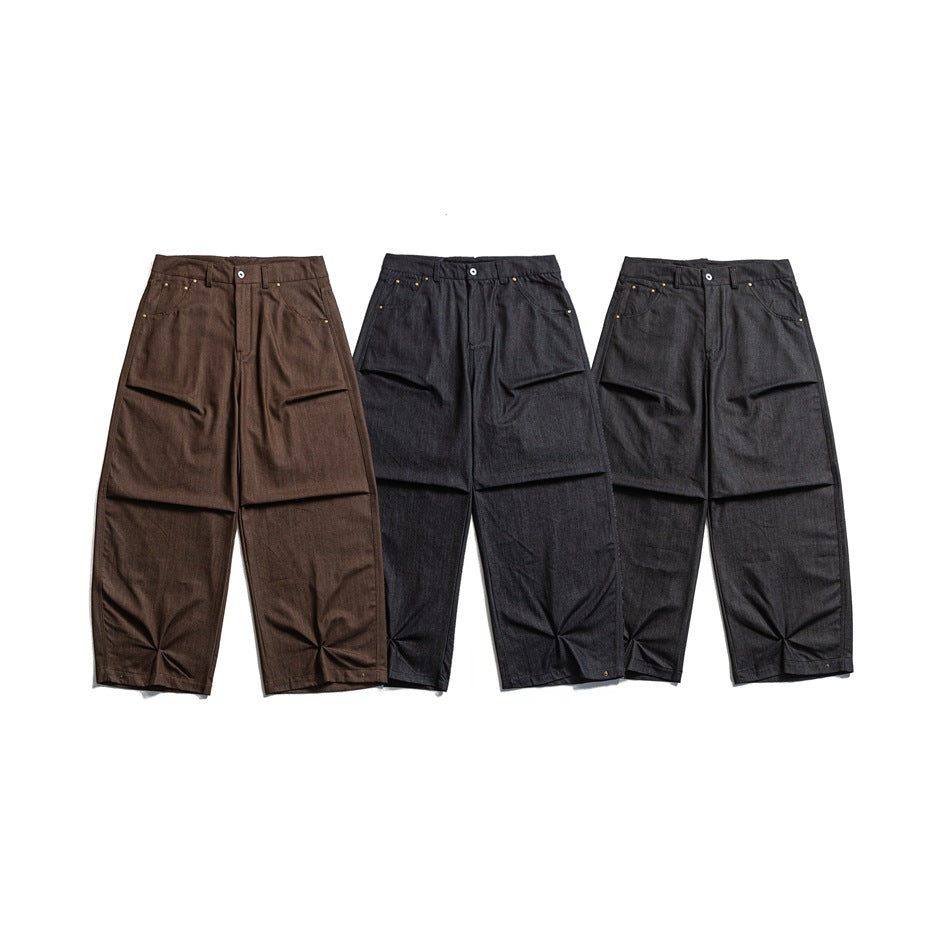 Three pairs of wide-leg trousers laid out from the front in brown and two dark charcoal shades.