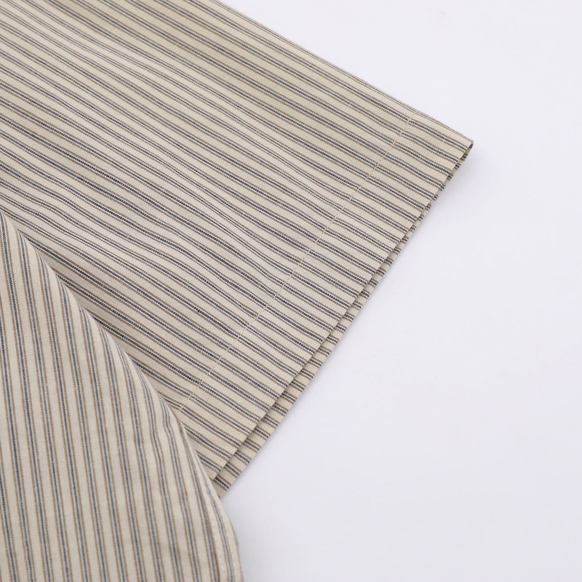Close-up of the striped beige shirt sleeve and hem against a white background.