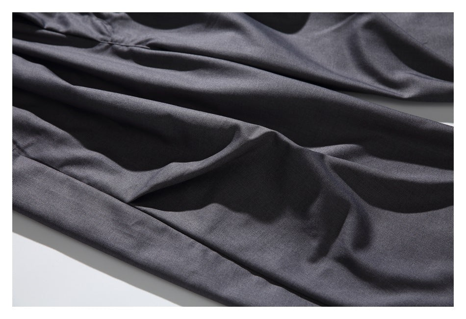 Close-up of charcoal trouser legs laid in soft folds, showing the smooth fabric and drape.