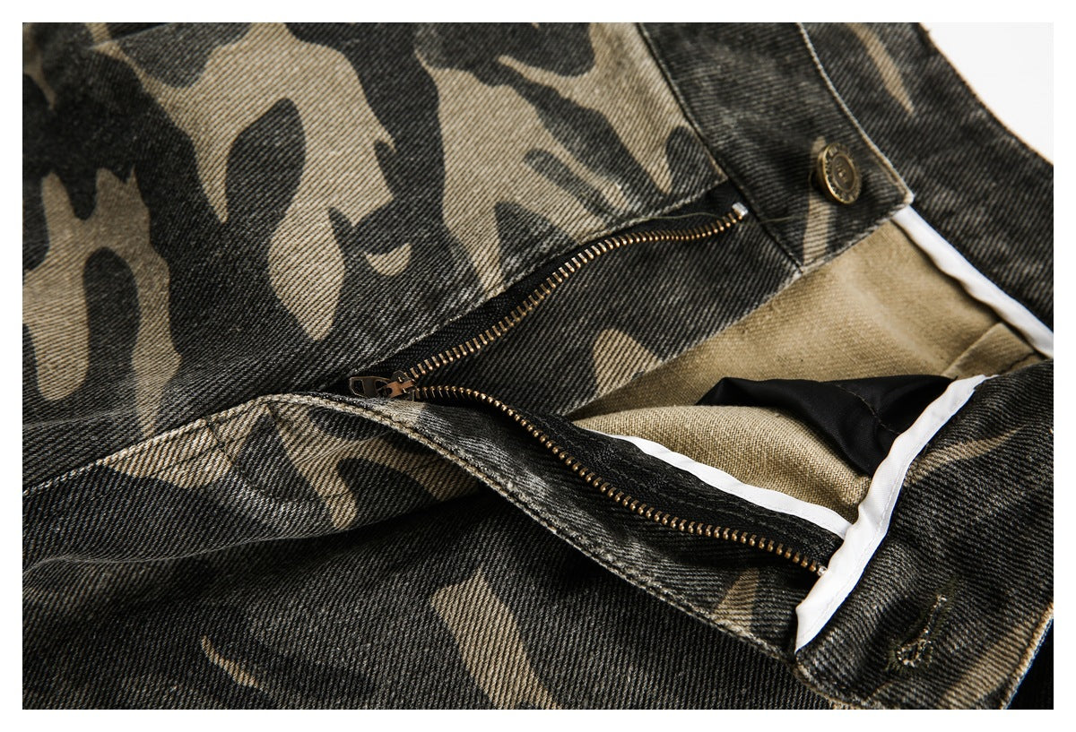 Close-up of camouflage trousers with an open brass-toned zipper fly and button fastening.
