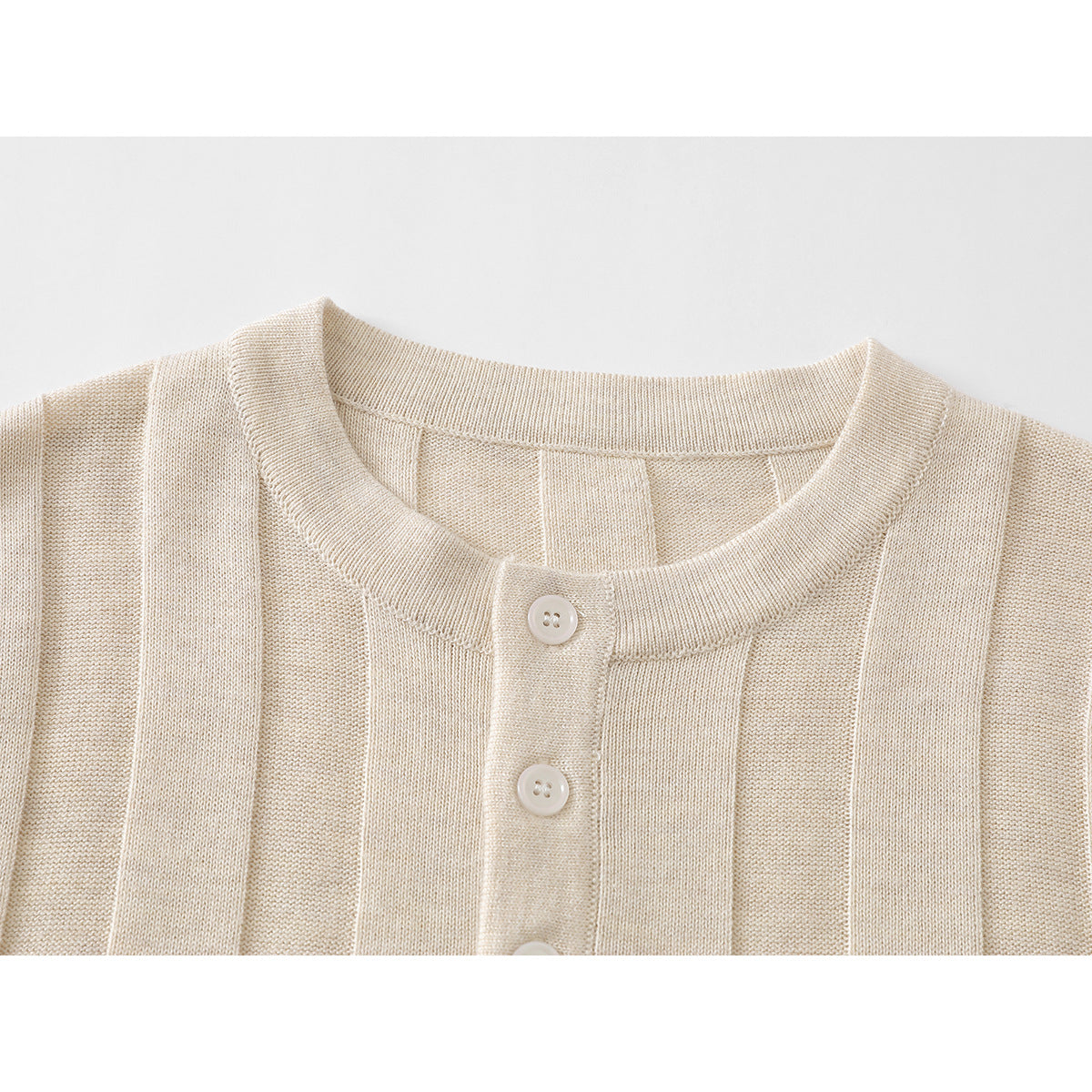 Close-up of a cream ribbed knit top with a round neck and three-button placket.