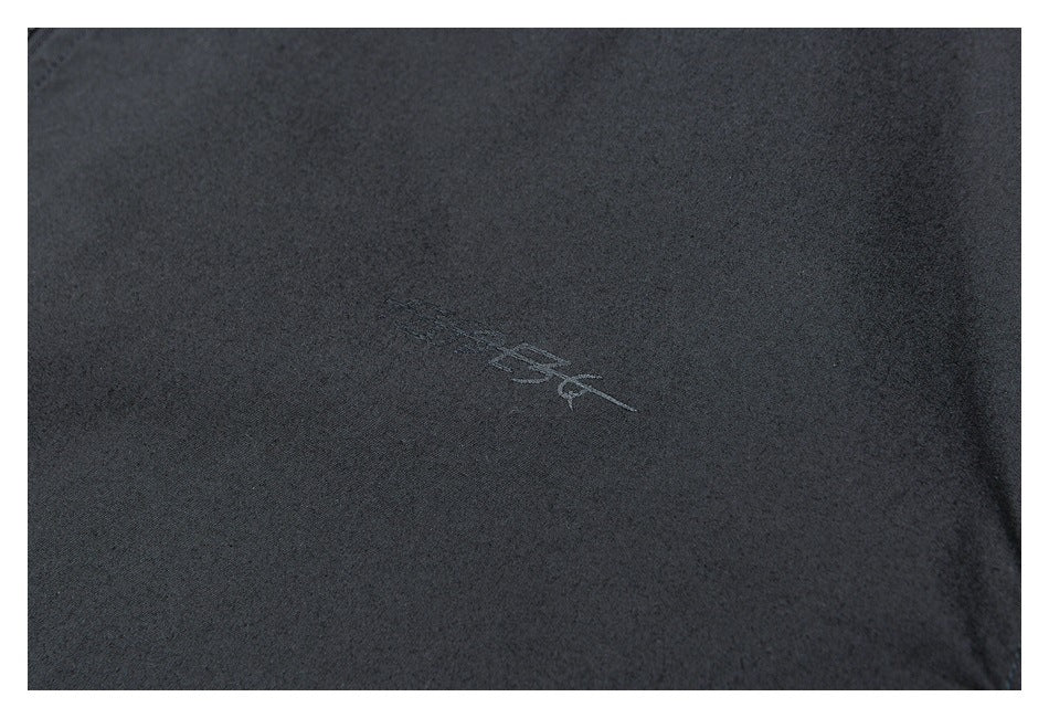 Close-up of a small tonal embroidered emblem on dark jacket fabric.