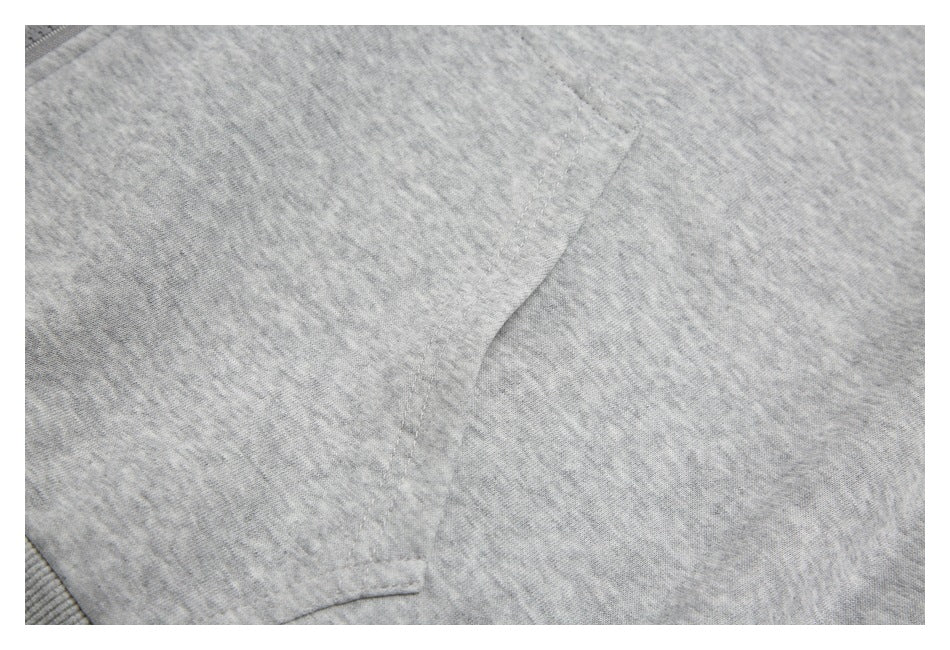 Close-up of a stitched pocket edge on light heather-gray fabric.