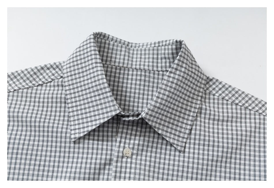 Close-up of the pointed collar and top button of a gray-and-white checked shirt.