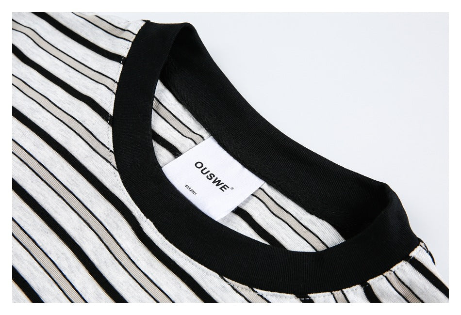 Close-up of a black crew neckline and white shirt with black stripes, showing the inner neck label.