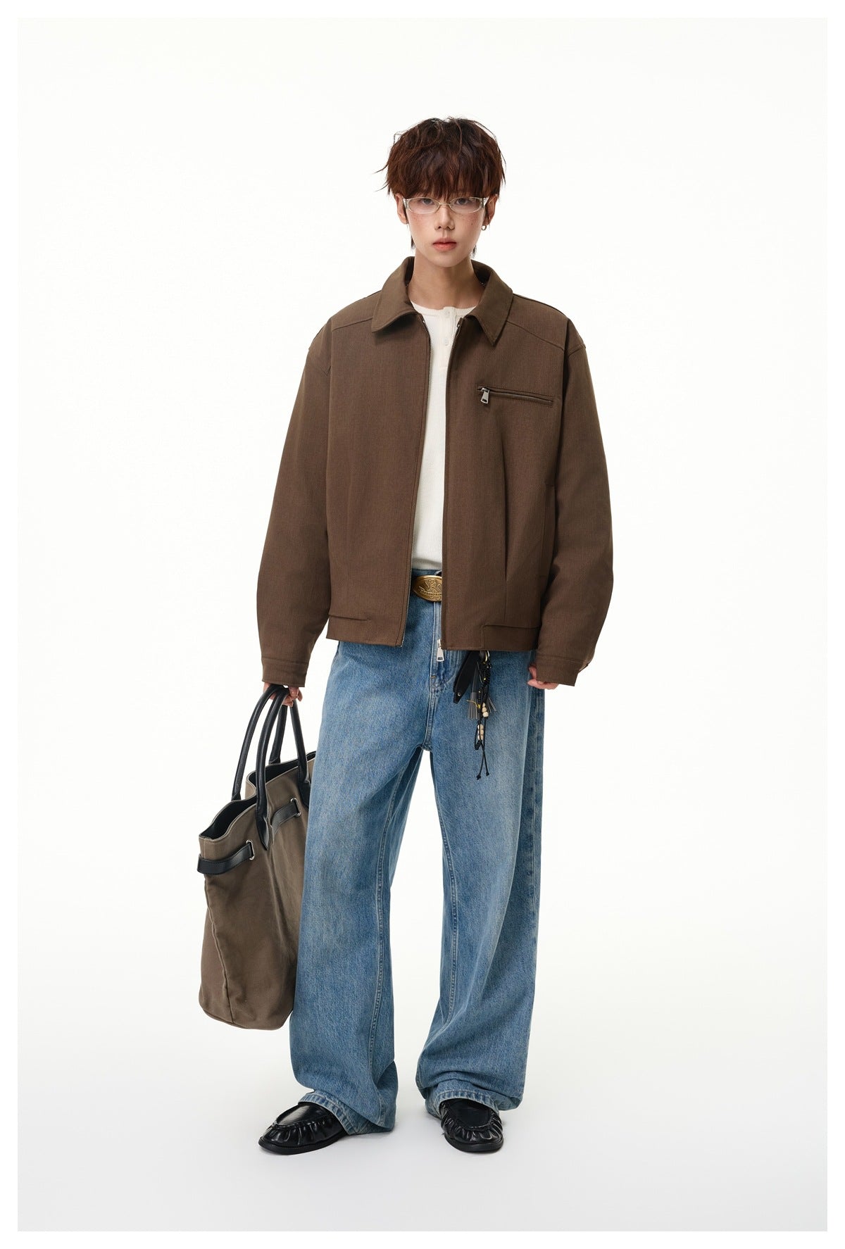 Full-length model wearing a brown zip-front jacket with a pointed collar and chest zip pocket, styled with blue jeans.