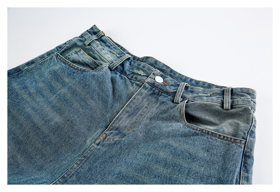 Angled close-up of the front waist, button, belt loops, and pockets of faded blue denim shorts.