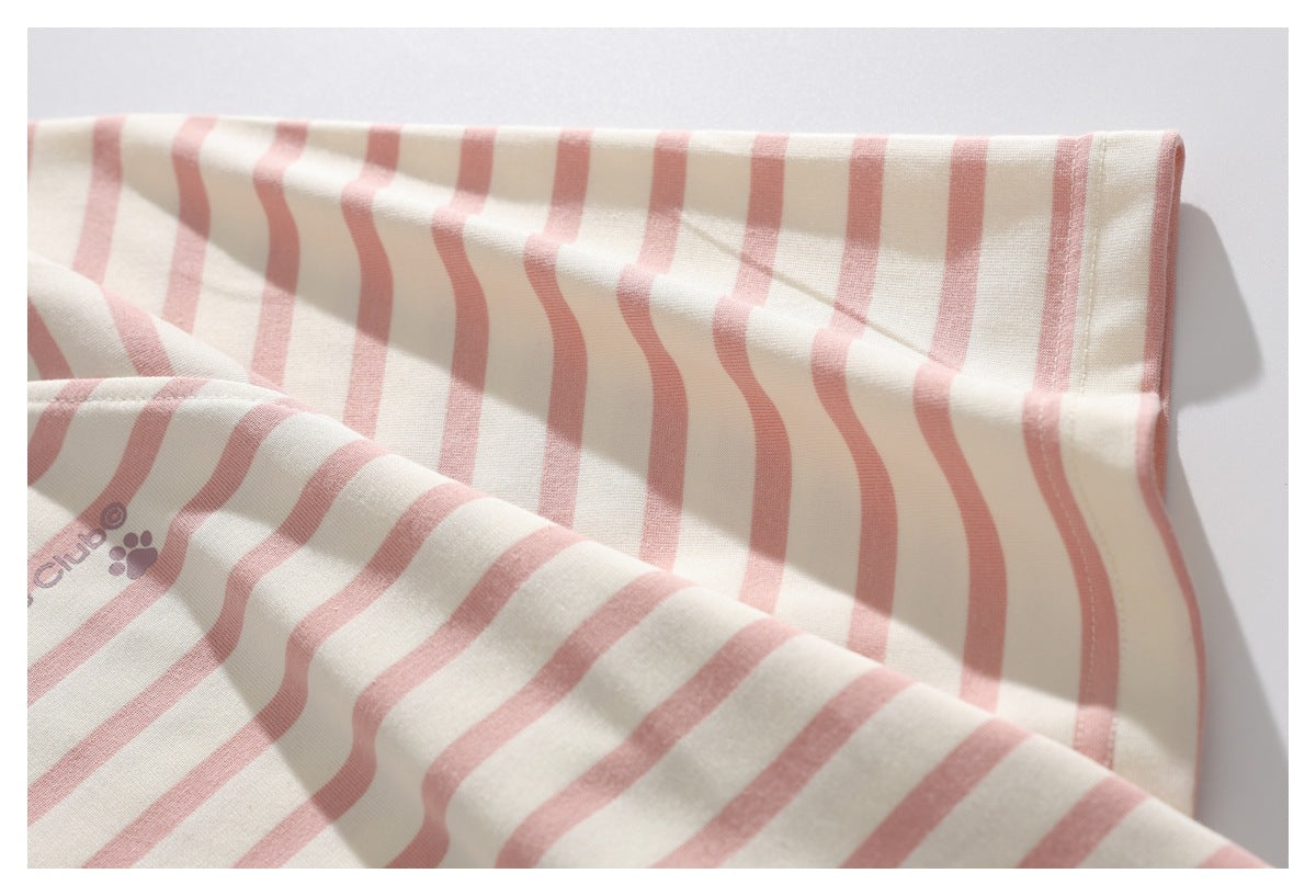 Close-up of a dusty pink striped sleeve and hem stitching on cream fabric, with a small printed paw and text motif.