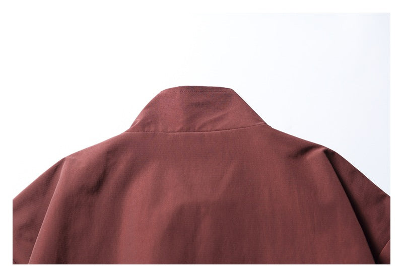 Upper back of a burgundy jacket with a raised collar, shown flat against a light background.