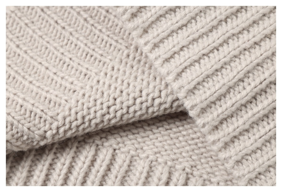 Close-up of thick cream knit fabric folded to show its textured stitches.