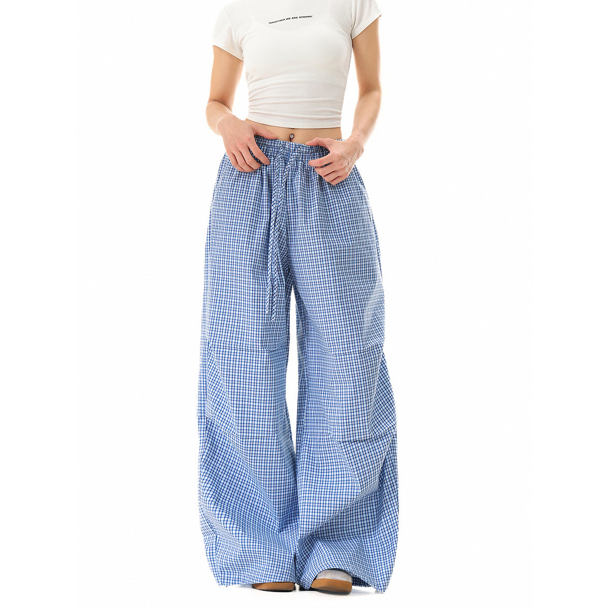 Front view of a model wearing loose blue-and-white check pants with an elastic drawstring waist.