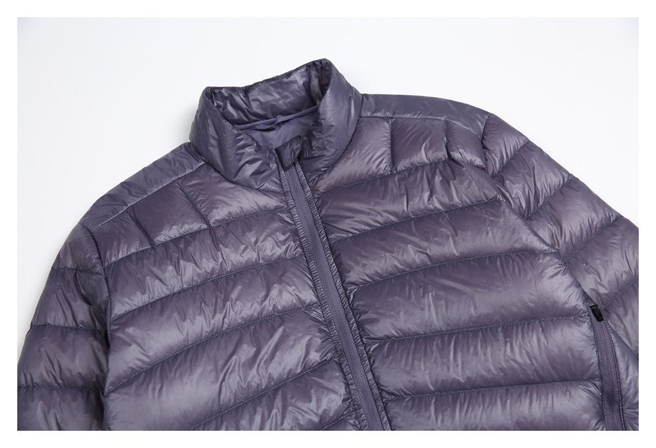 Close view of a charcoal-purple quilted jacket front, showing the high collar, zipper, and horizontal stitching.