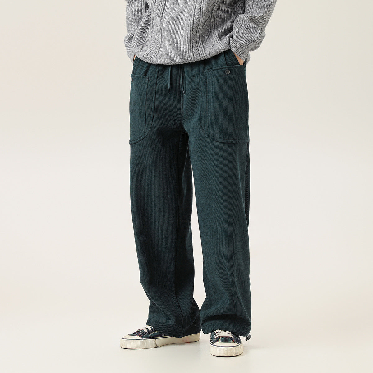 Front view of a model wearing dark teal wide-leg ribbed pants with a drawstring waist and two large front pockets.