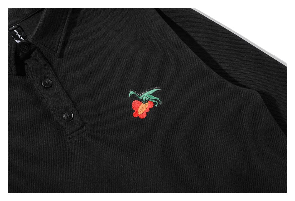 Close-up of a small red-and-green embroidered motif on the chest of a black shirt.