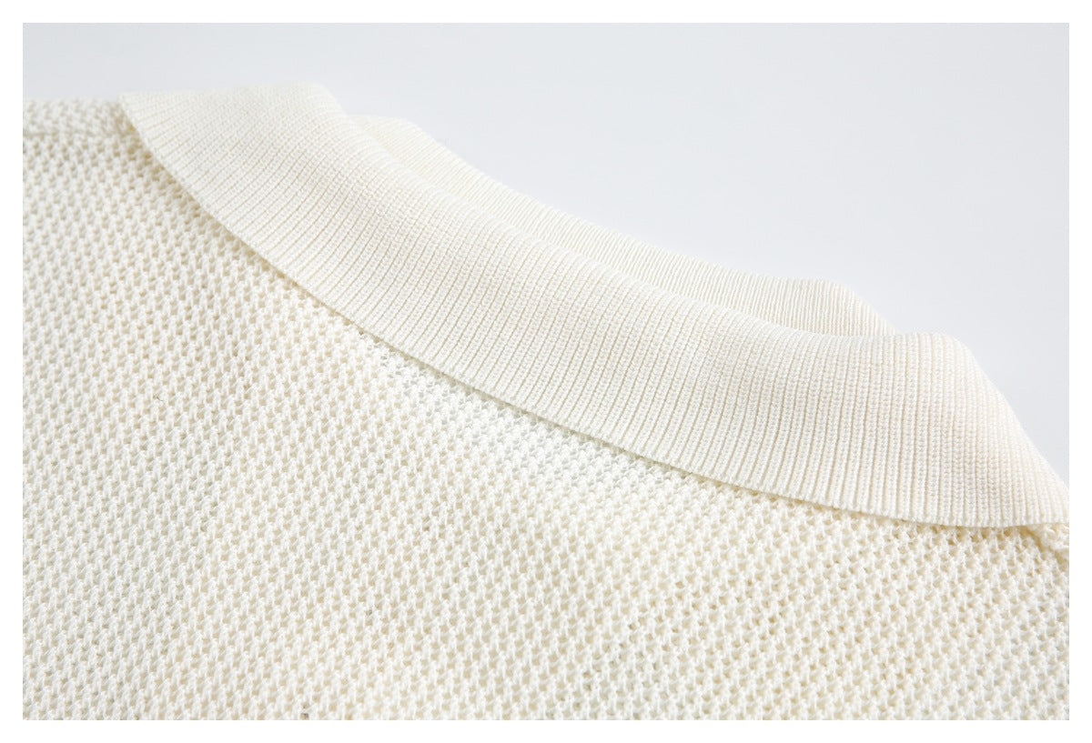Close-up of the ivory sweater's wide ribbed neckline and textured knit body.