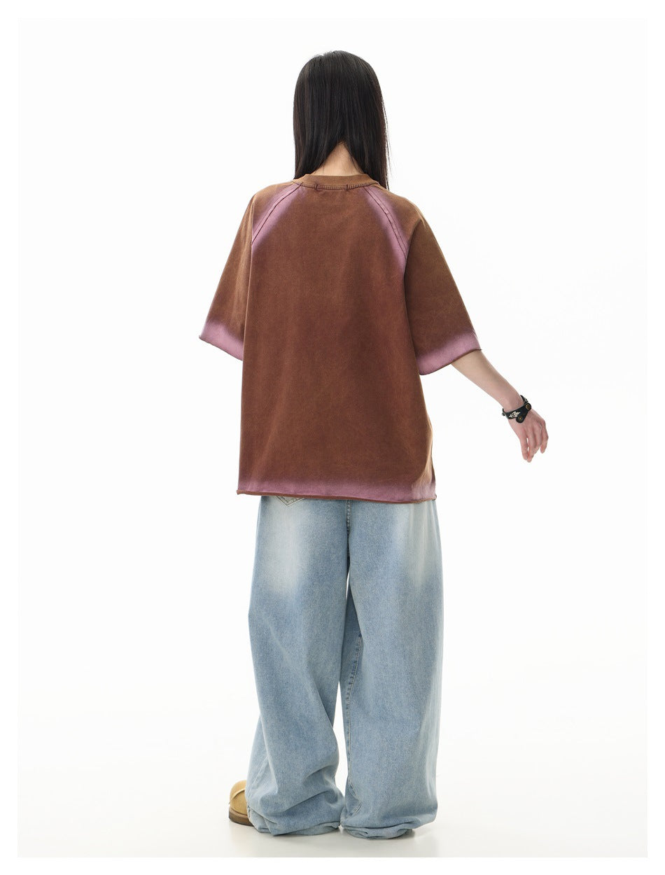 Rear view of a model wearing an oversized brown shirt with mauve faded accents on the raglan seams, sleeves and hem.