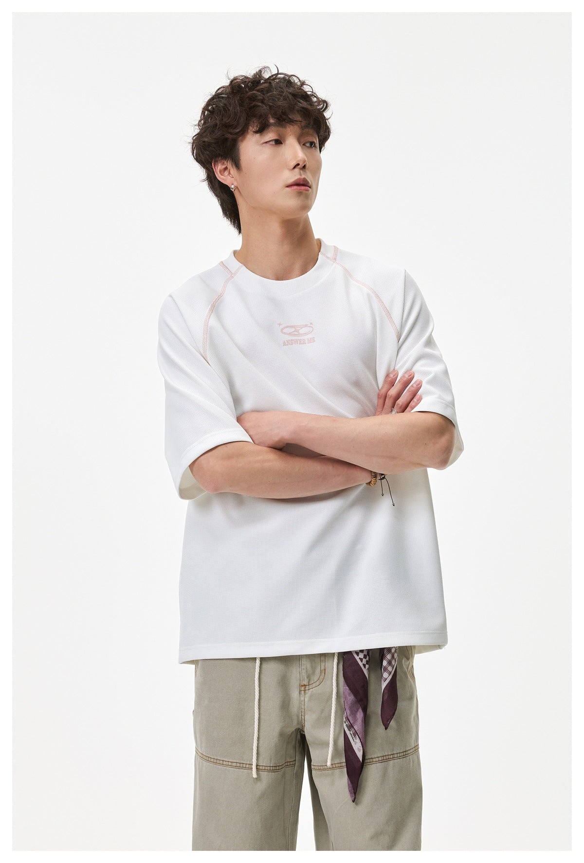 Model wearing an oversized white short-sleeve shirt with pale pink seam details and a small chest graphic.