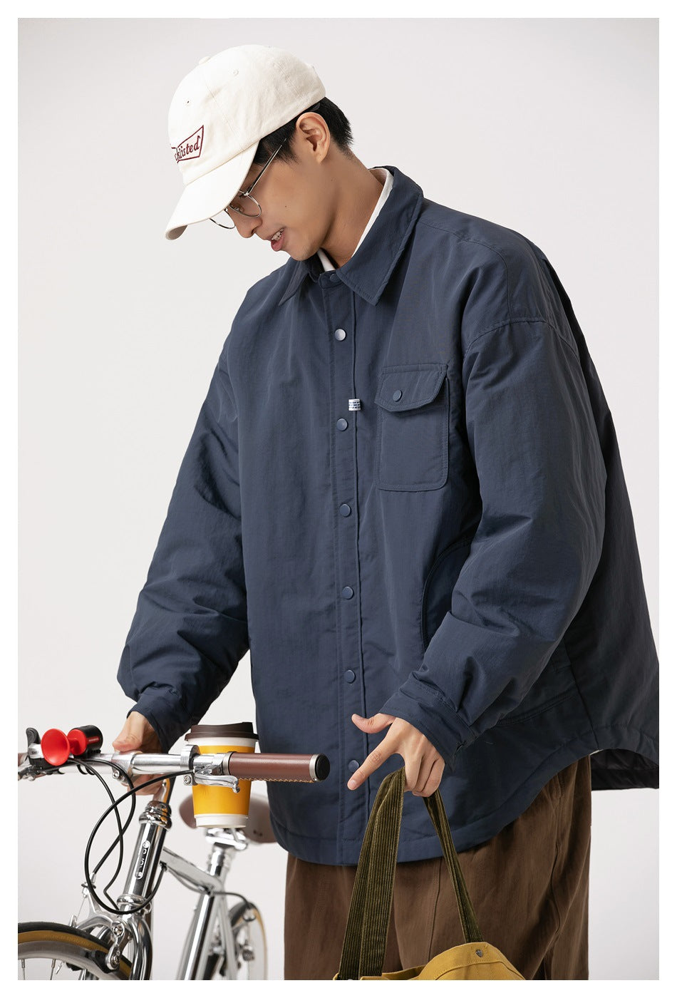 Close view of a model wearing a navy jacket, showing its collar, snap front, chest flap pocket, and roomy sleeves.