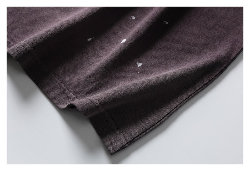 Close-up of the dark plum shirt's lower hem with scattered small white paint-like marks.