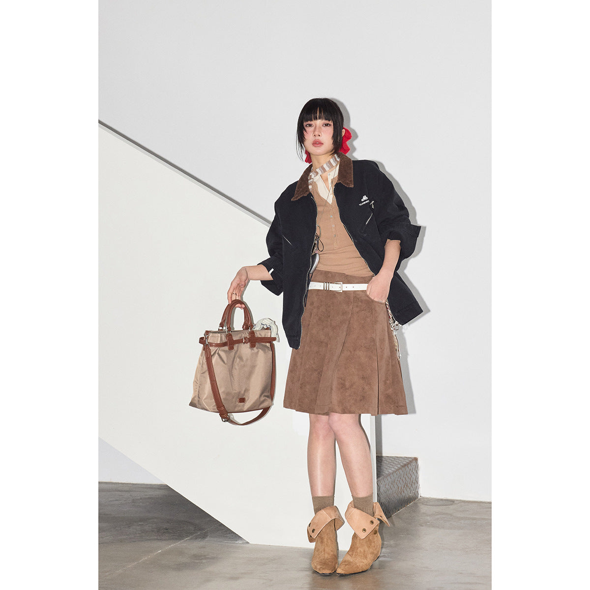 Model wearing a black jacket with a brown collar, tan top, and brown suede-look skirt.