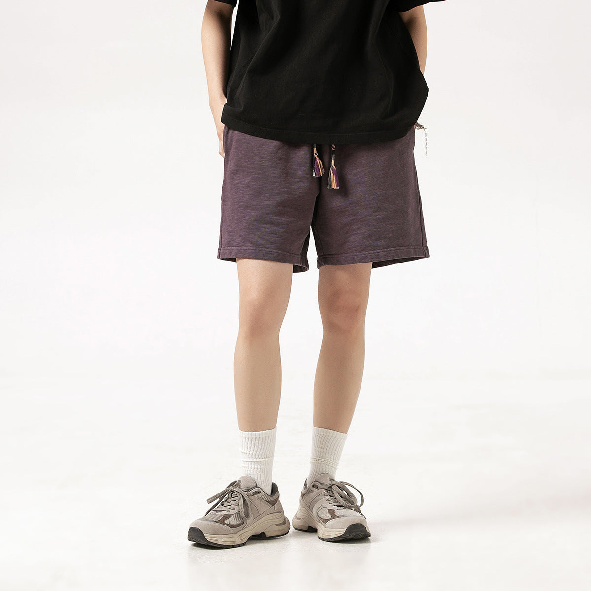 Front view of a model wearing dark plum shorts with tasseled drawstrings.