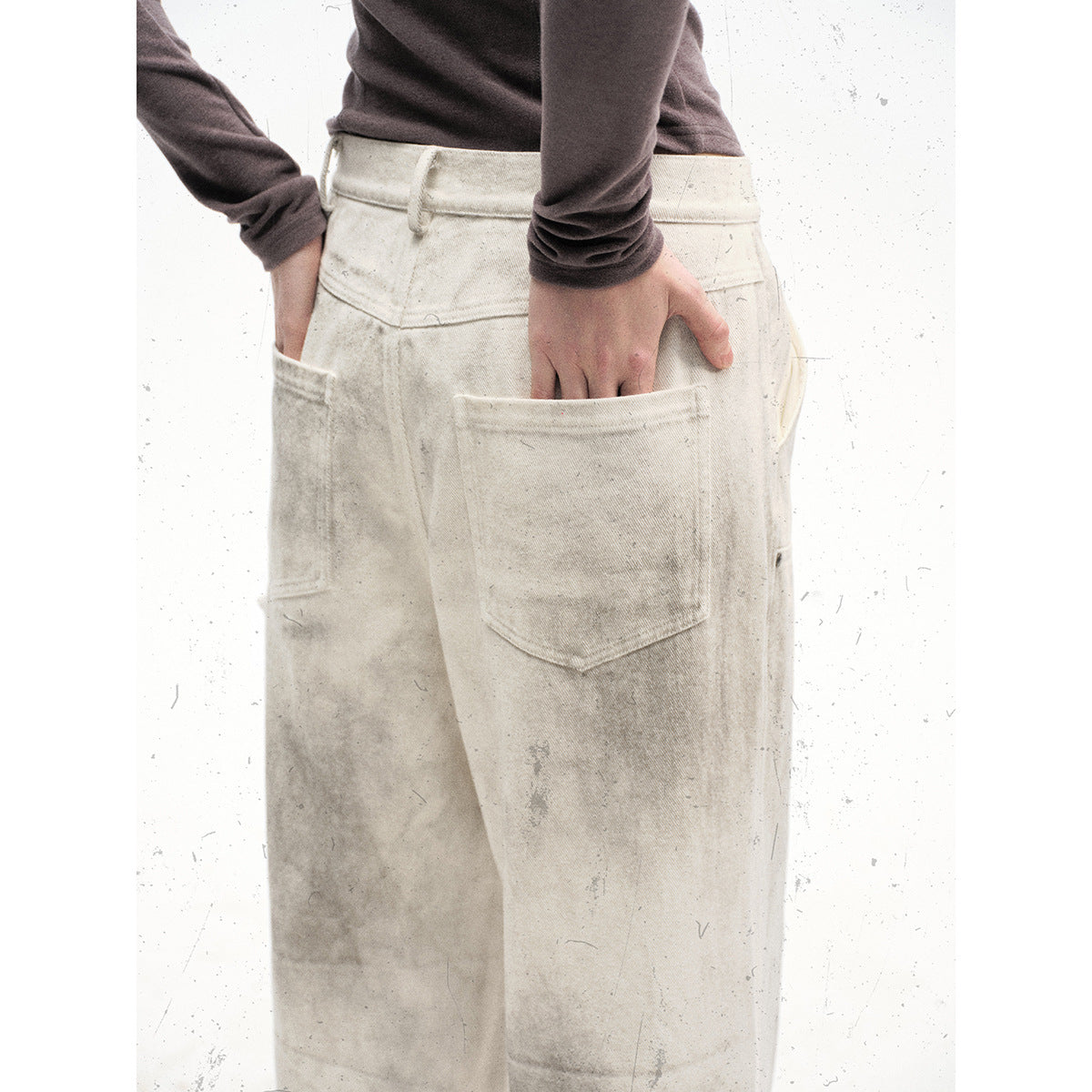 Close-up of the back of off-white mottled pants, showing a large patch pocket and belt loops.