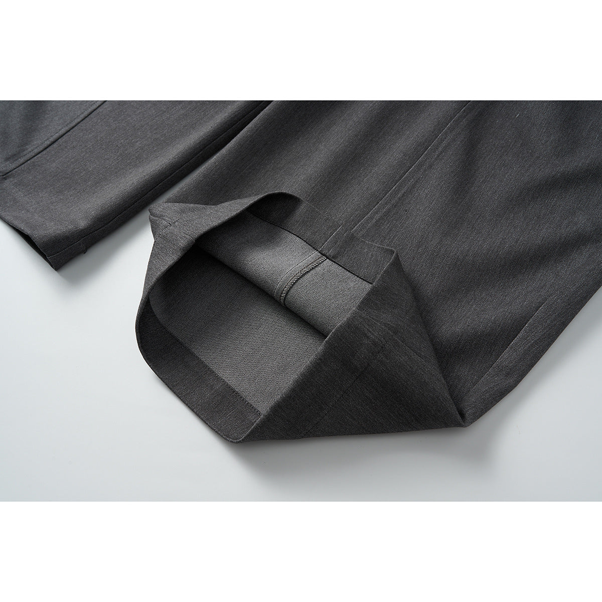 Close-up of a charcoal gray trouser leg hem, folded to show the inside stitching.