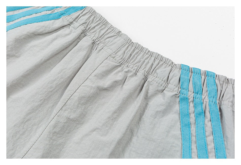 Close-up of the elastic waistband and turquoise accents on light gray shorts.