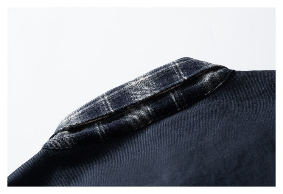 Close-up of a dark navy jacket collar with navy, gray, and cream plaid fabric on the underside.