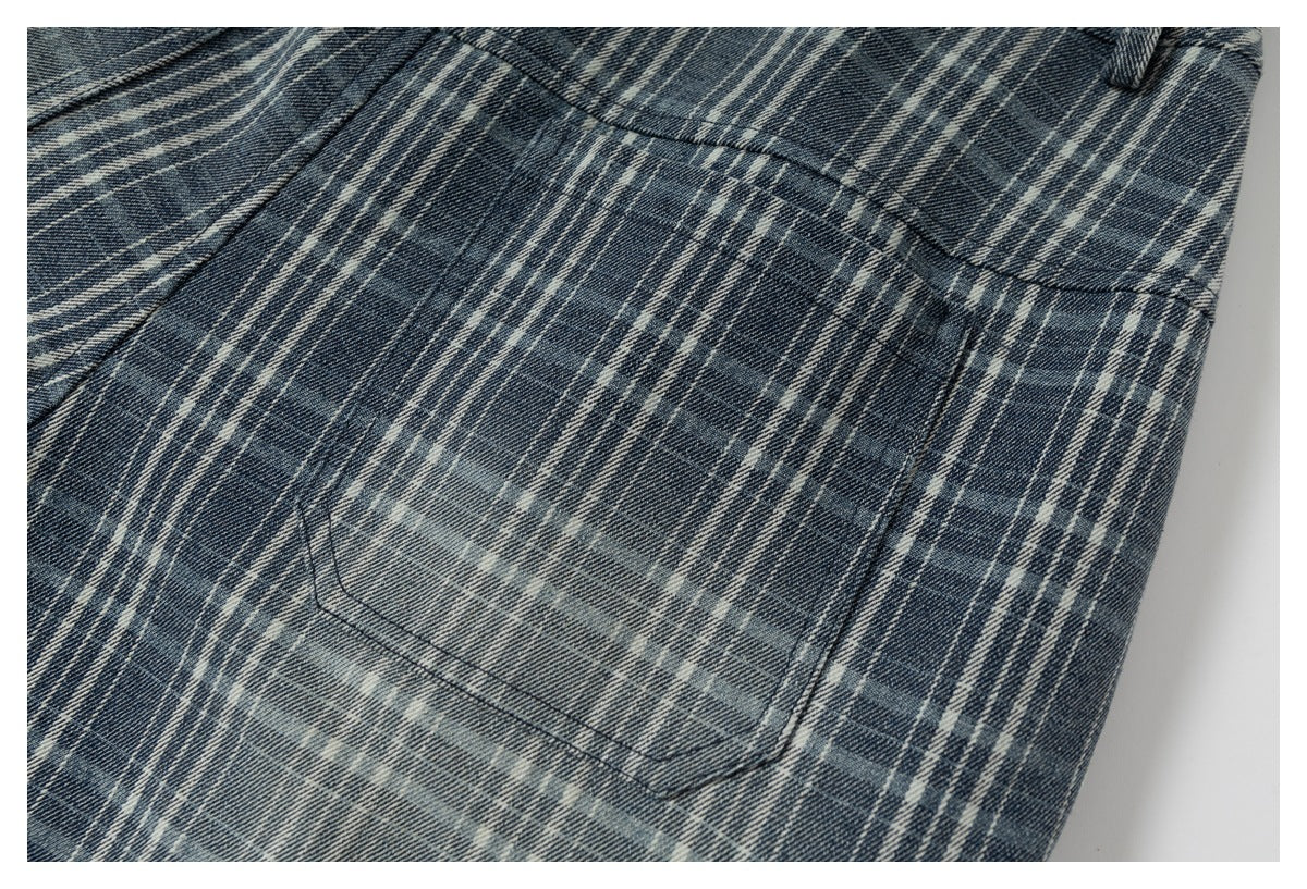 Close-up of a stitched patch pocket on blue-gray plaid fabric.