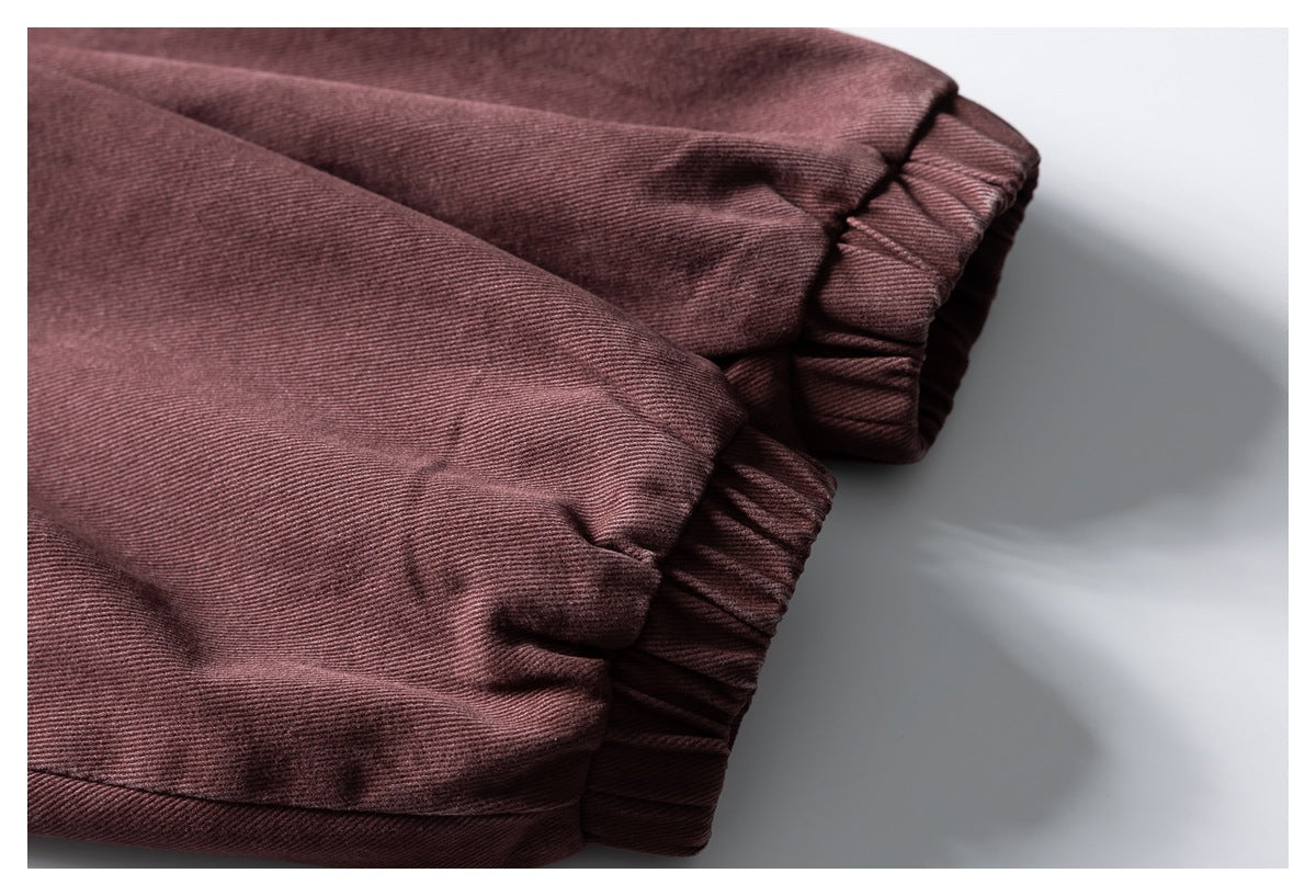 Close-up of two gathered elastic openings on a muted burgundy garment.