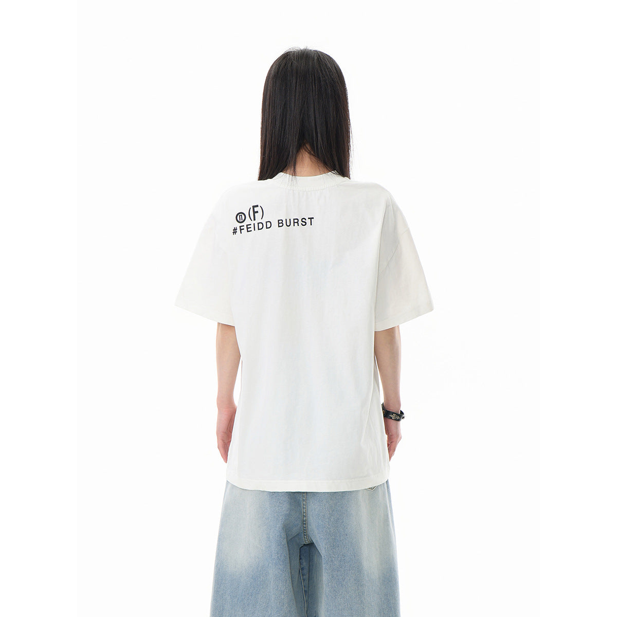 Back view of a model wearing an off-white oversized T-shirt with small black text across the upper back and wide light-wash