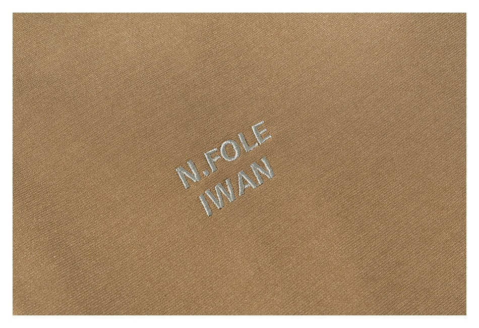 Close-up of white embroidered lettering on the tan jacket fabric.