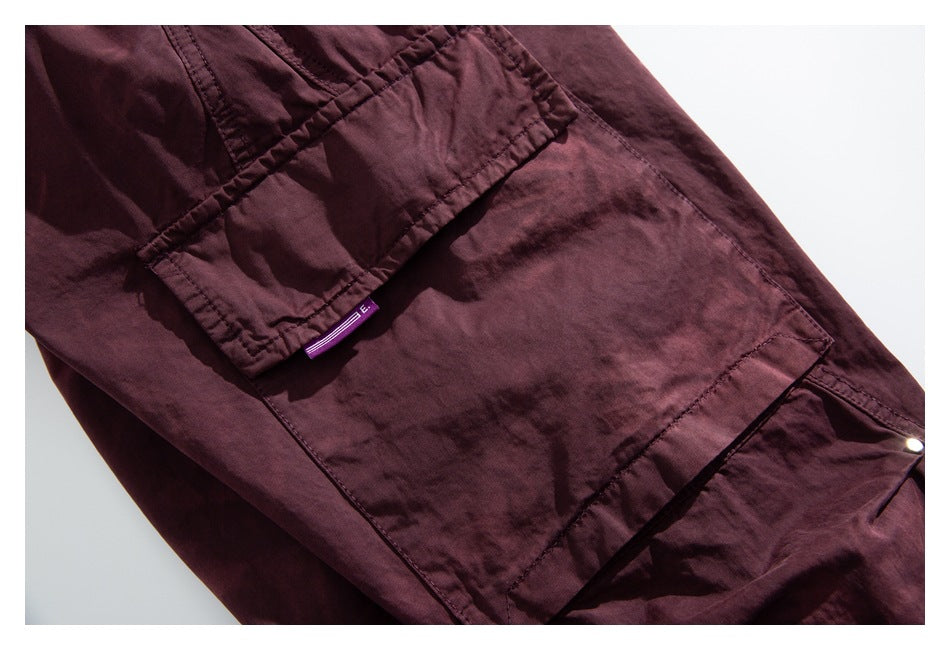 Close-up of a burgundy cargo pocket flap and stitched panel, with a small purple fabric tab.
