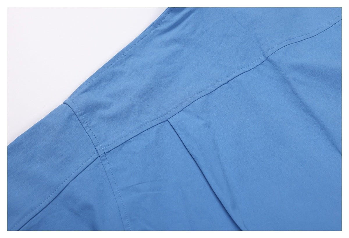 Close-up of blue shirt fabric showing intersecting stitched seams and a folded edge.