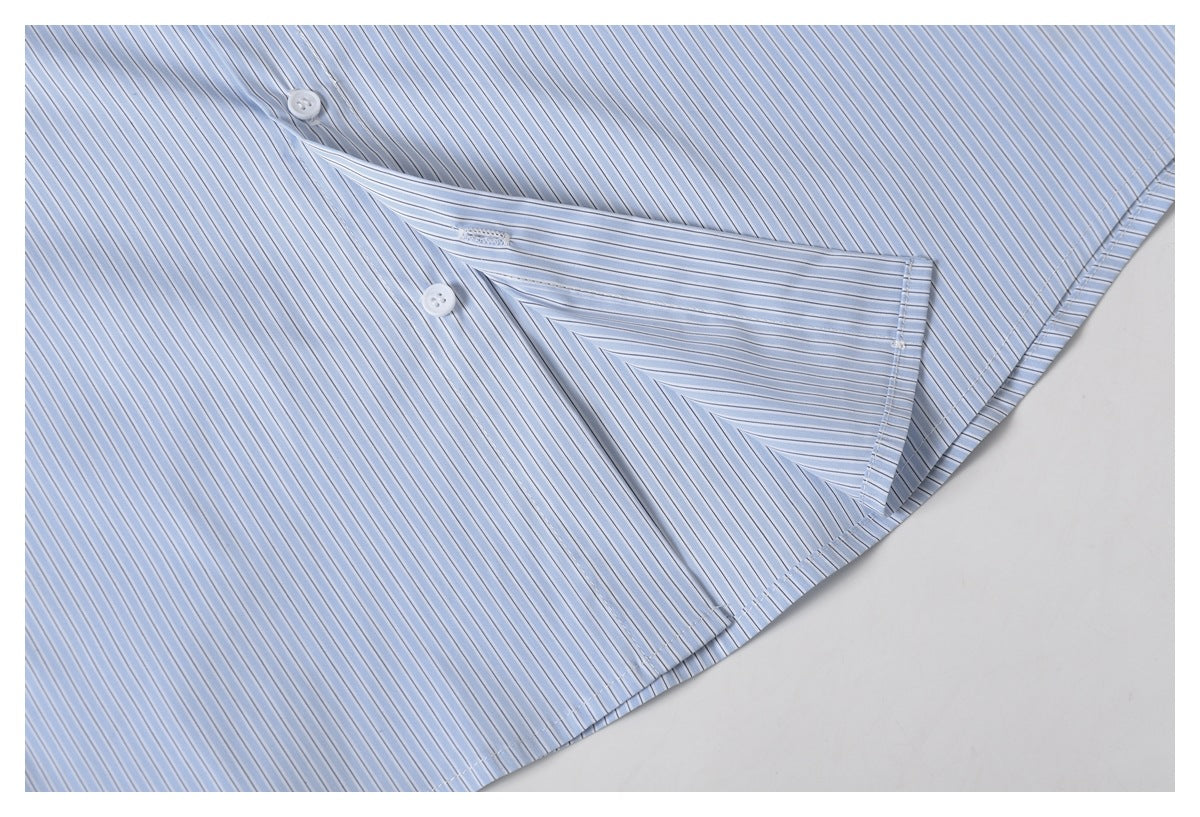 Close-up of a light blue pinstriped shirt pocket, stitching, and white buttons.