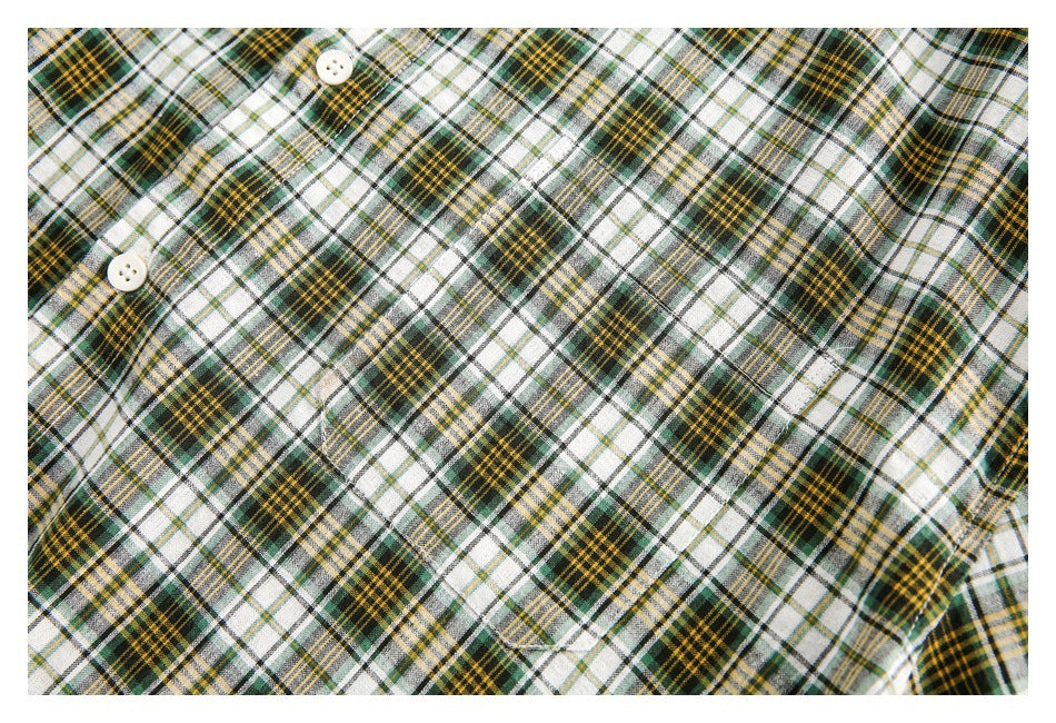 Close-up of the plaid shirt's front fabric, button, and pocket stitching.