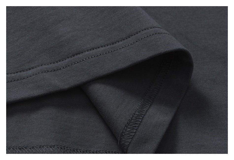 Close-up of a dark charcoal garment hem with topstitching and an overlocked inner seam.