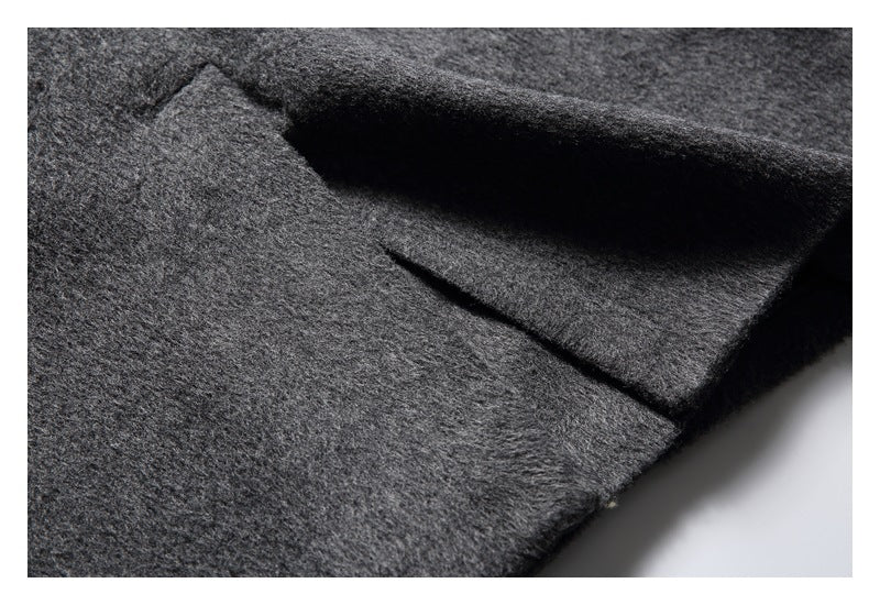 Close-up of a charcoal gray coat front, showing a folded lapel and a narrow seam or pocket opening.