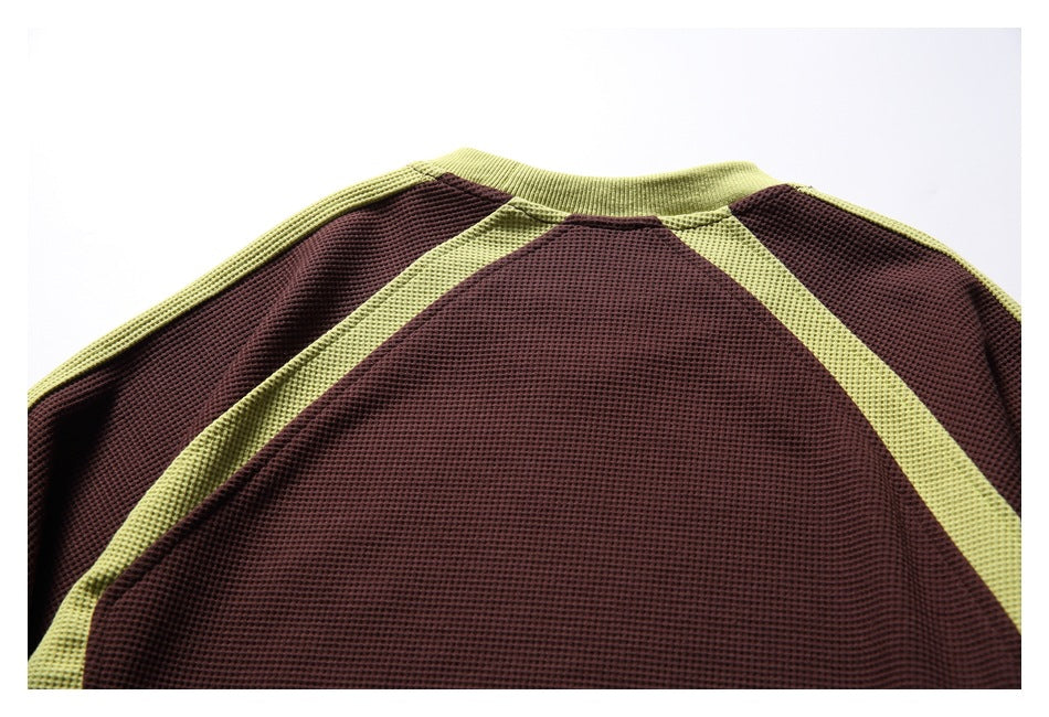 Cropped back view of a burgundy waffle-knit top with chartreuse raglan panels and collar.