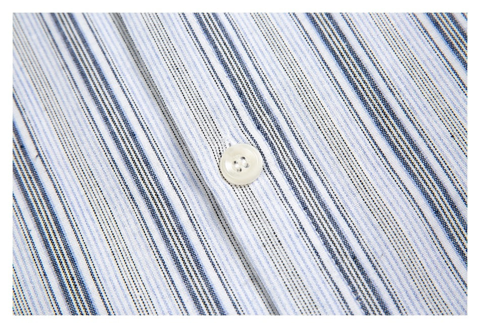 Close-up of a white four-hole button on white fabric with narrow blue and gray stripes.