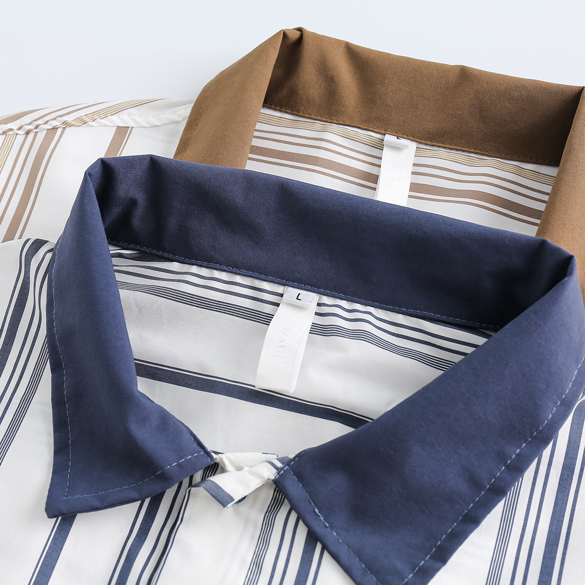 Close-up of navy and tan collars on white shirts with matching vertical stripes.