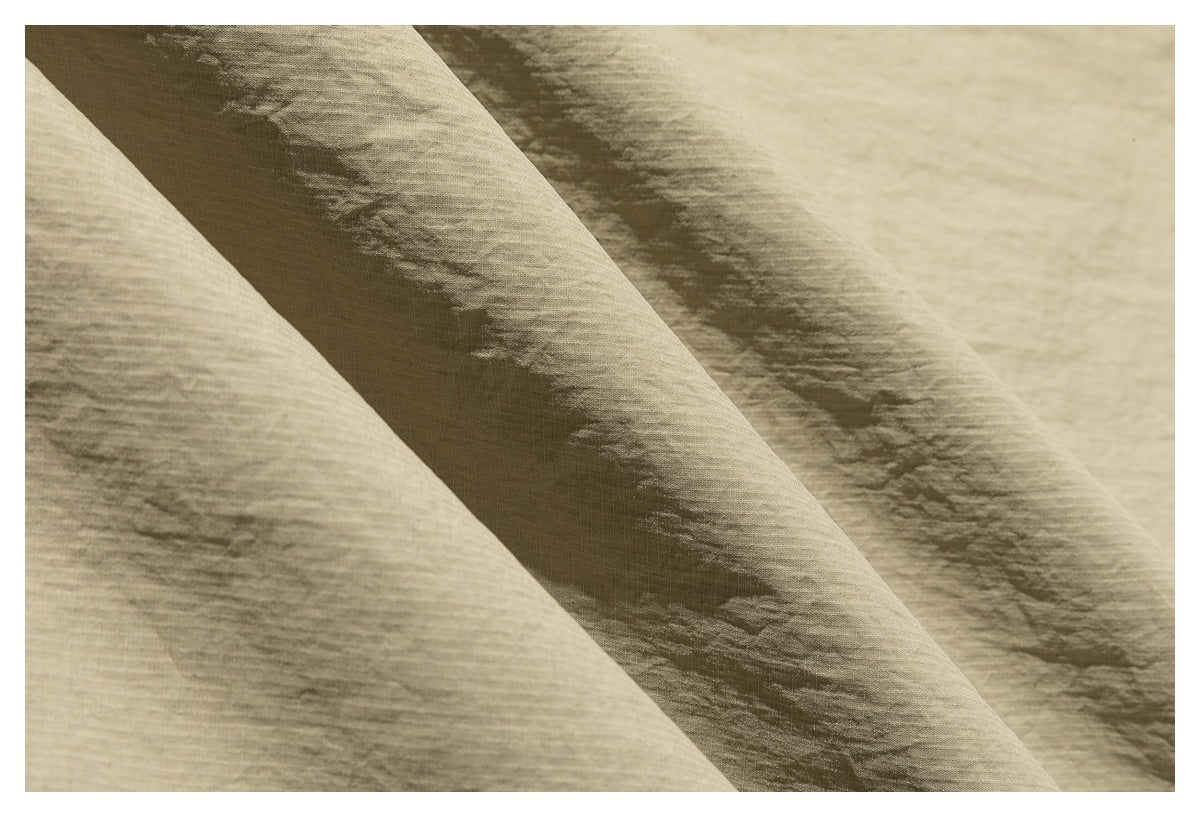 Macro view of the khaki jacket's subtly textured fabric draped in folds.