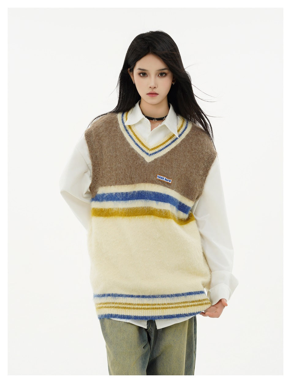 Model wearing a brown and cream striped V-neck knit vest over a white collared shirt with green-washed pants