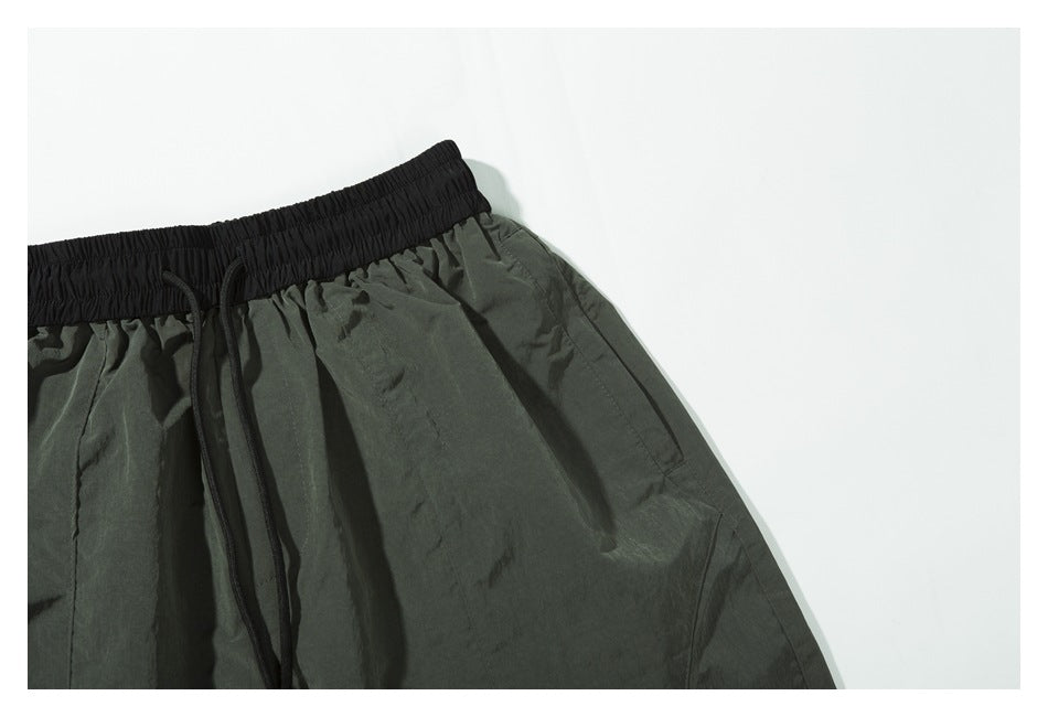 Close-up of the dark olive shorts' front side, waistband, drawcords and side pocket.