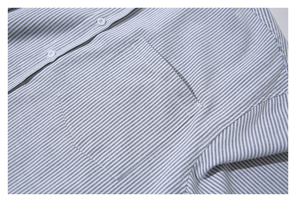 Close-up of a gray-and-white striped shirt showing its chest pocket, buttons, and fabric pattern.