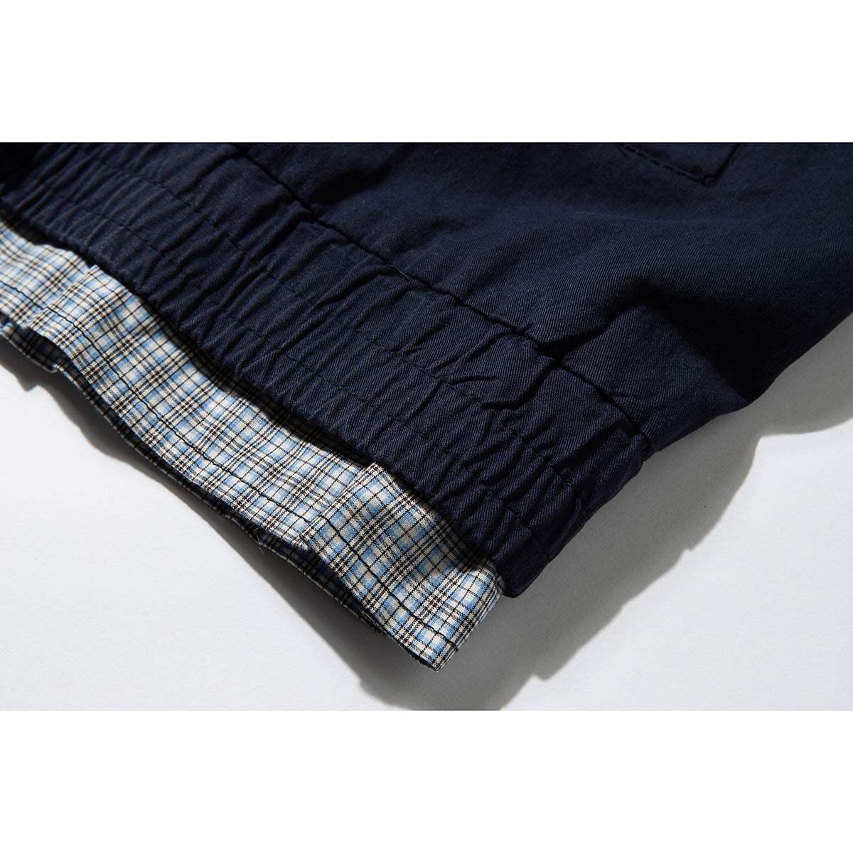 Close-up of the navy jacket hem, showing beige-and-blue plaid lining and stitched seams.