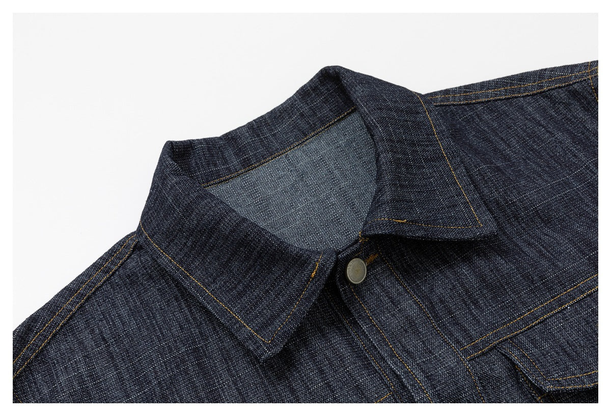 Close-up of the dark indigo denim jacket's pointed collar, topstitching, and front button.